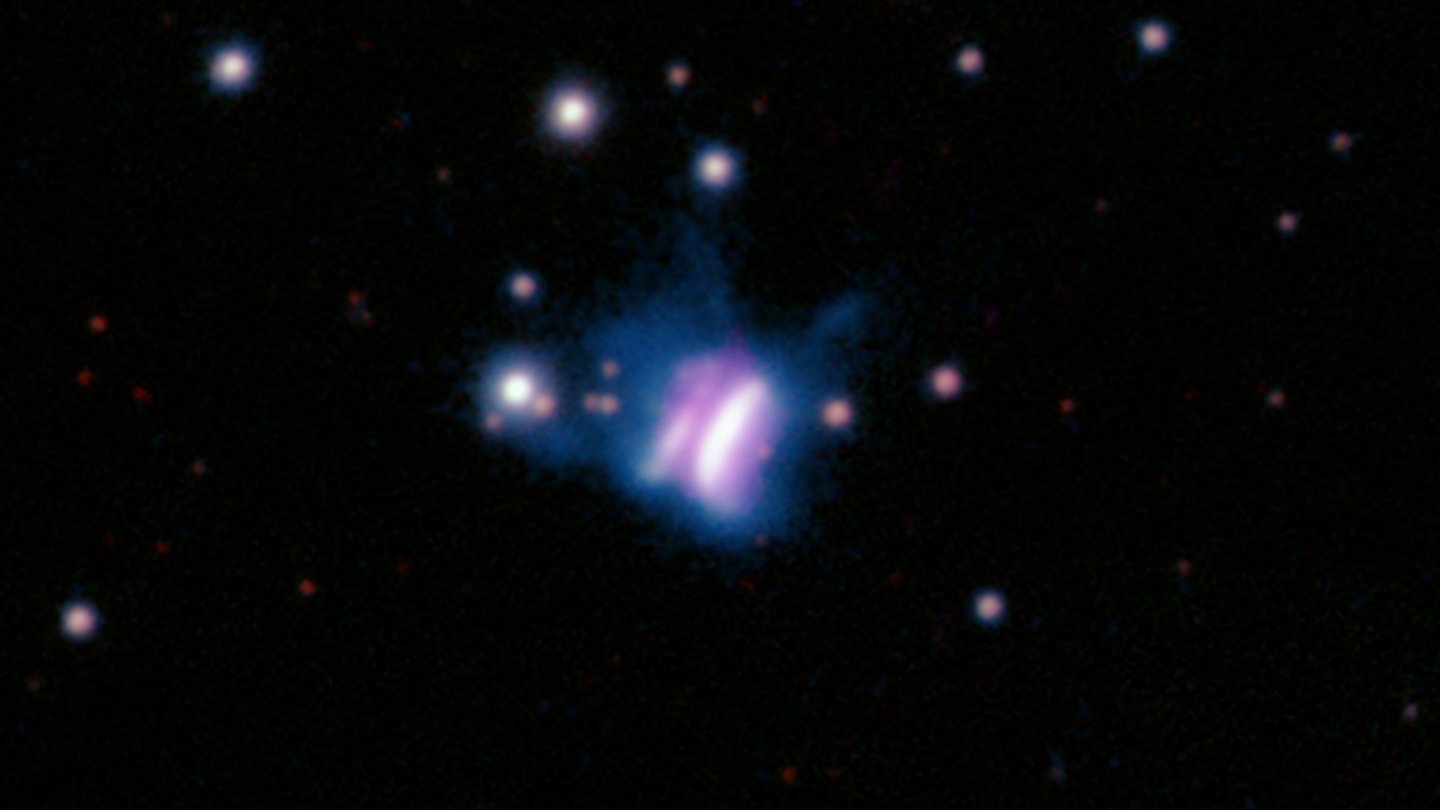 Pan-STARRS and SMA image: The center of this composite image shows IRAS 23077, likely the largest planet-forming disk ever seen, which looks like a giant cosmic butterfly. Data from the Submillimeter Array (SMA) at radio wavelengths is shown in pink, and data from Pan-STARRS at optical wavelengths is shown as a color image. Most of the nearby stars appear as white or red. The star in the center of IRAS 23077 is not visible because its light is blocked by the surrounding disk, which is viewed from the side. The blue PanSTARRS data for IRAS 23077 shows the smallest dust grains, with sizes of only a few micrometers. These dust grains are elevated into the uppermost layers of IRAS 23077's disk and appear as two bright lobes, similar in shape to the wings of a butterfly. The two faint filaments in IRAS 23077's northern region could be remnants from IRAS 23077's formation. The pink SMA data shows larger dust grains, with sizes of about one millimeter. These larger dust grains are coincident with the midplane of the planet-forming disk, where dust grains settle and grow to larger sizes and eventually form planets.